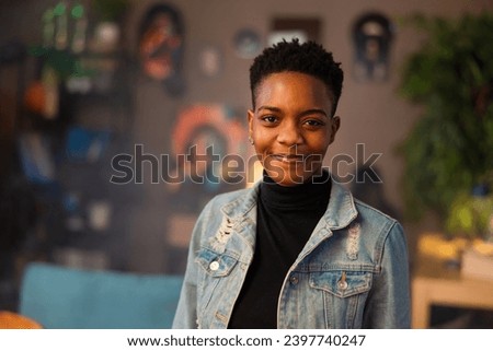 Portrait of delighted afro american woman with short dark hair smiling at camera confidentely staying in the beautiful cozy living room. Royalty-Free Stock Photo #2397740247