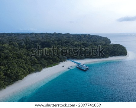 Aerial view of the beautiful Peucang Island Pier Harbor within the Ujung Kulon National Park at Banten. Landscape of the blue ocean with beautiful white sand beaches on the edge of the island.