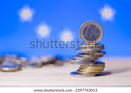 Stack of Euro coins on a table with flag of EU in background illustrating financial concepts of European Union like GDP, buying power, economic crisis...  Royalty-Free Stock Photo #2397743013