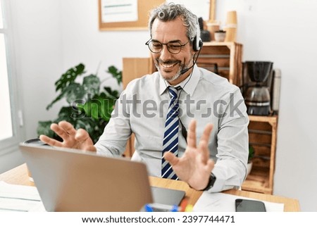 Middle age grey-haired man call center agent smiling confident working at office Royalty-Free Stock Photo #2397744471