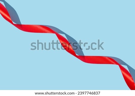 Red silk ribbon on bright blue background. Elegant decorative greeting card or invitation idea with copy space.