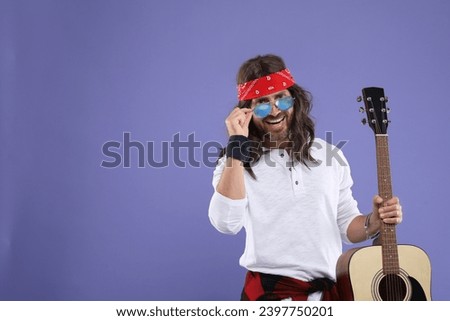 Stylish hippie man with guitar on violet background, space for text