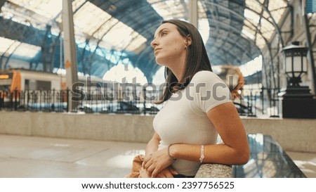 Beautiful girl traveler sits on the platform of the railway station waiting for the train