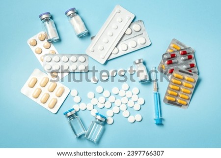 Medicine on the table. Colorful pills, capsule, ampullae and syringe on a blue background Royalty-Free Stock Photo #2397766307