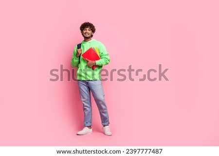 Full body photo of young indian student guy in green trendy sweatshirt with rucksack behind hold books isolated on pink color background