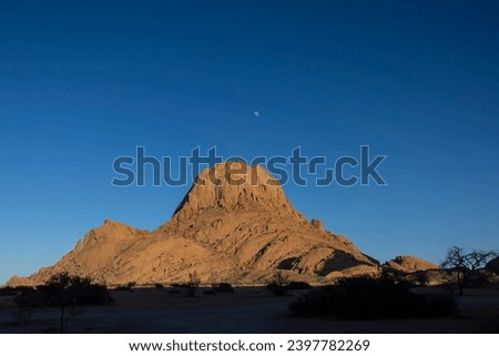 Spitzkoppe.  The moon setting behind the Spitzkoppe Mountain in Namibia