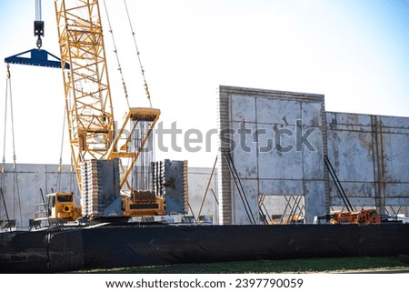 Crane and heavy-duty machines at mega warehouse construction site precast concrete wall panels, prefabricated building material, steel scaffolding framework, safety fence, walling system, Texas. USA Royalty-Free Stock Photo #2397790059