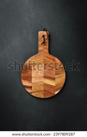 Kitchen wooden cutting board on a dark stone background. Top view. Free space for text.