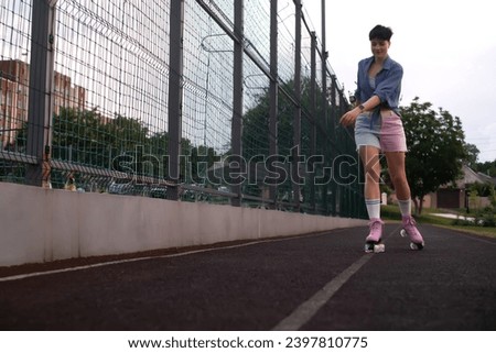 Young woman on roller skates riding outdoors on a city street. Smiling brunette girl with roller skates on a sunny day