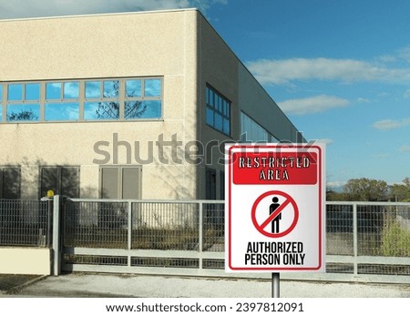 Sign with text Restricted Area Authorized Person Only on fence near factory building outdoors Royalty-Free Stock Photo #2397812091