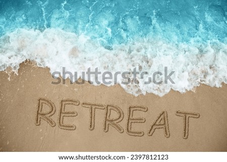 Word Retreat drawn on sand near sea, above view