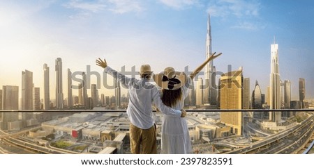 A happy tourist couple on vacation time stands on a balcony and enjoys the panoramic view of the Dubai city skyline, UAE Royalty-Free Stock Photo #2397823591