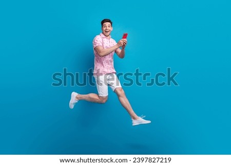Full size profile portrait of astonished person jump use smart phone empty space isolated on blue color background
