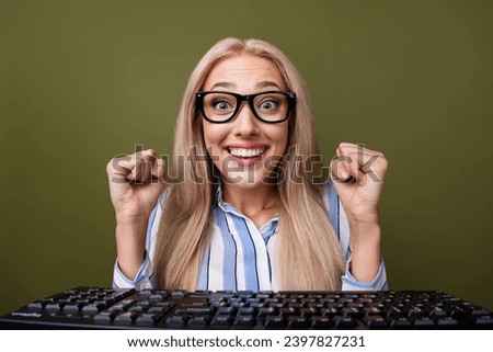 Photo portrait of blonde pretty young girl keyboard raise fists excited dressed stylish striped outfit isolated on khaki color background