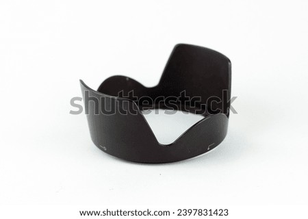 A black lens hood in the shape of a flower petal sits on a white background.