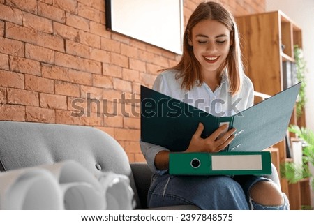 Young businesswoman with document folders in office Royalty-Free Stock Photo #2397848575
