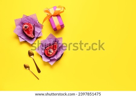 Delicious fruit cakes, gift box and spoons for Halloween celebration on yellow background