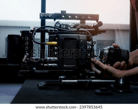 Close Up human hand inserting the cinema lens into a movie camera mount.