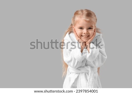 Cute little girl in bathrobe on light background