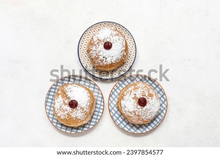 Plates with tasty donuts for Hanukkah celebration on light background