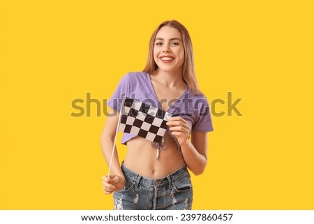 Happy young woman with racing flag on yellow background