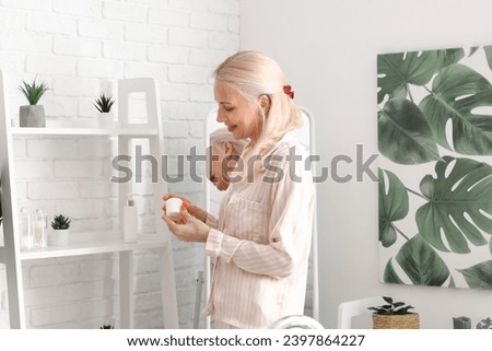 Mature woman with jar of cream in bathroom