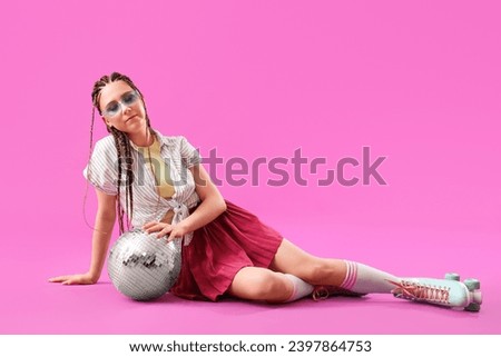 Young woman with dreadlocks and roller skates on pink background