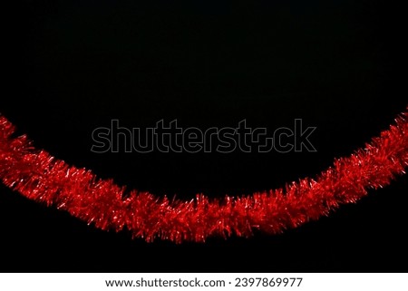 Red tinsel, glitter, trumpery on black color background with copy space. Christmas dark mock up template for your design.  Royalty-Free Stock Photo #2397869977