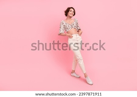 Full size photo of good mood cute girl dressed trousers blouse palms in pockets look at sale empty space isolated on pink color background