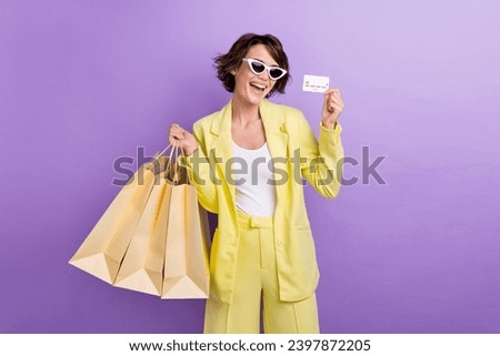Photo of impressed cheerful woman dressed yellow jacket dark eyewear rising bank card shoppers isolated purple color background