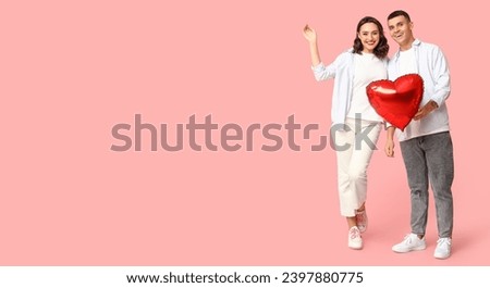Happy young couple with heart-shaped balloon on pink background with space for text. Valentine's Day celebration