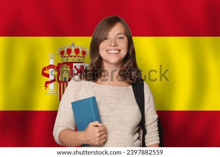 Cheerful woman student against Spanish flag background. Travel, education and learn language in Spain concept Royalty-Free Stock Photo #2397882559