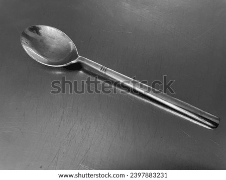 interior top view photo of a silver metal spoon on a silver stainless steel work top background table