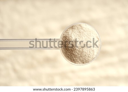 Collagen powder in a plastic measuring spoon above beige background, top view Royalty-Free Stock Photo #2397895863
