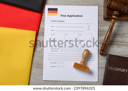 Immigration to Germany. Visa application form, passport, gavel and stamp on wooden table, flat lay