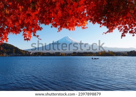 Beautiful landscape view of Mount Fuji with light falling through autumn leaves in Kawaguchiko and a boat silhouette passing by the lake.  Royalty-Free Stock Photo #2397898879