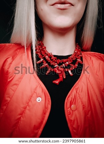 Red wide coral necklace Ukrainian traditional jewelry style Red triple necklace with pendant on blonde Irregular beaded jewellery, female accessory Fashion neck accessory Woman without face Red jacket Royalty-Free Stock Photo #2397905861