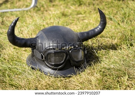Black leather motorcycle helmet with glasses and devil horns in the grass