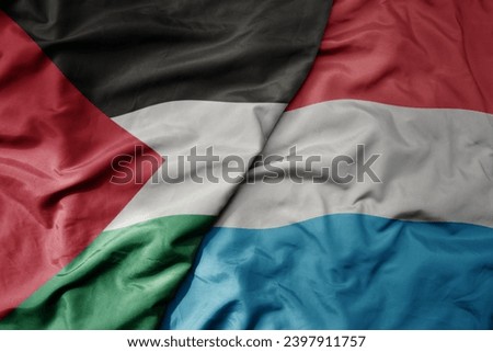 big waving national colorful flag of luxembourg and national flag of palestine . macro
