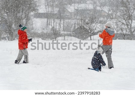 Children have fun outside in the winter during snowfall. Kids play snowballs. Winter entertainment Royalty-Free Stock Photo #2397918283