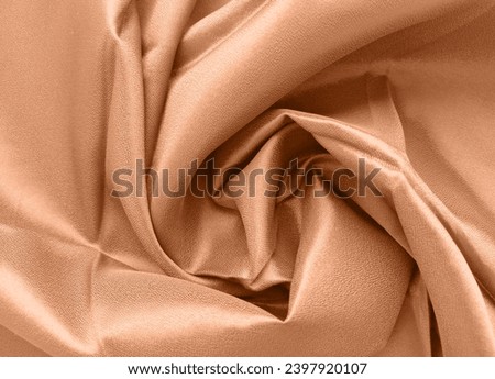 Silk fabric folded with beautiful curves with shadows. New color of year 2024 Peach Fuzz