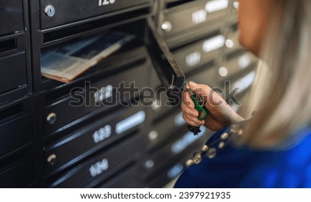 Woman checking mailbox in apartment building. Royalty-Free Stock Photo #2397921935