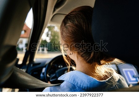 Rear view of young female with seat belt. American Teen Learning Driver's Education