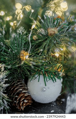 Christmas white ball on a festive tree. Blurred background and bokeh. Shallow depth of field. Copy space. The artistic intend and the filters. Film style old lens. Airy atmosphere.