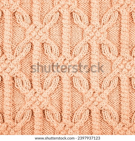 Knitted peach background. Large knitted fabric with a pattern. Close-up of a knitted blanket. Demonstrating the colors of 2024 - Peach Fuzz.