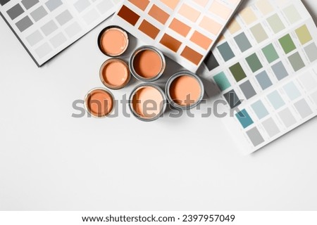 Tiny sample paint cans during house renovation, process of choosing paint for the walls, Peach Fuzz color of the year 2024, color charts on background Royalty-Free Stock Photo #2397957049