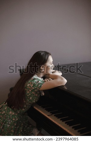 woman in green dress sitting near piano