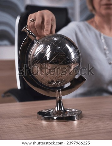 Close-up of a tabletop decorative globe for this aged woman chooses a direction on a trip