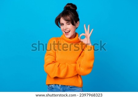 Photo of cheerful flirty lady wear knitted pullover winking showing okey sign isolated blue color background