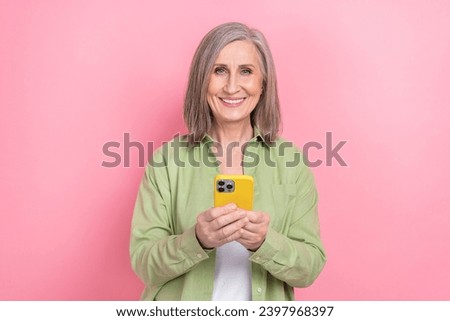 Portrait of charming pensioner woman wear khaki stylish shirt use yellow case apple iphone customer review isolated on pink color background